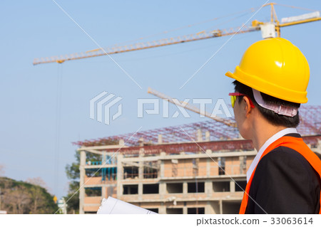 engineer wearing a orange shirt holding blueprint engineer wearing a orange shirt holding blueprint 33063614