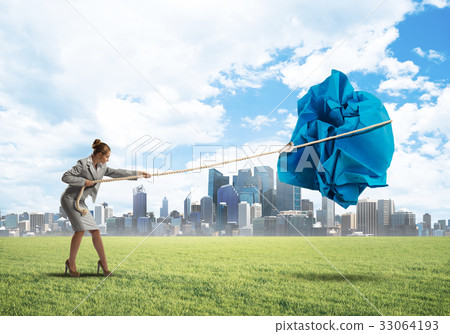 Woman pulling with effort big crumpled ball of paper as creativity sign Woman pulling with effort big crumpled ball of paper as creativity sign 33064193