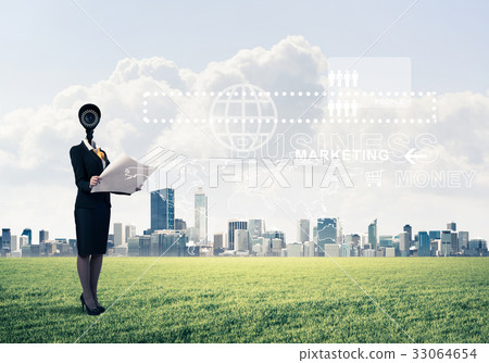 Camera headed woman standing on green grass against modern citys 33064654