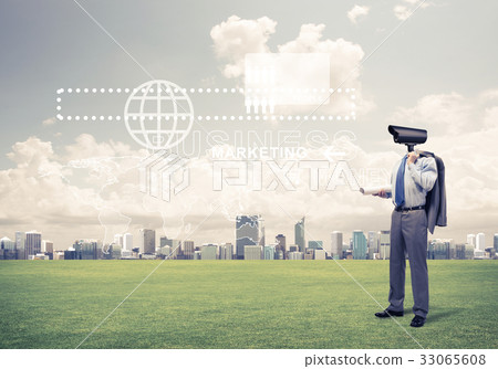 Camera headed man standing on green grass against modern citysca Camera headed man standing on green grass against modern citysca 33065608