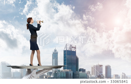 Attractive businesswoman on metal tray playing fife against cityscape background 33065841