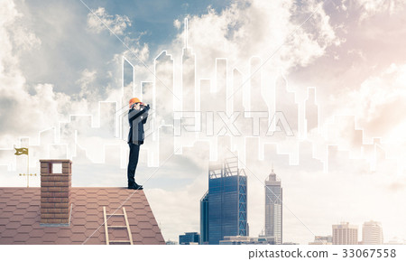 Engineer man standing on roof and looking in binoculars. Mixed m Engineer man standing on roof and looking in binoculars. Mixed m 33067558