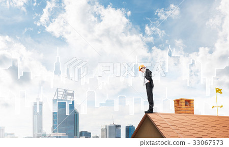Engineer man standing on roof and looking down. Mixed media Engineer man standing on roof and looking down. Mixed media 33067573