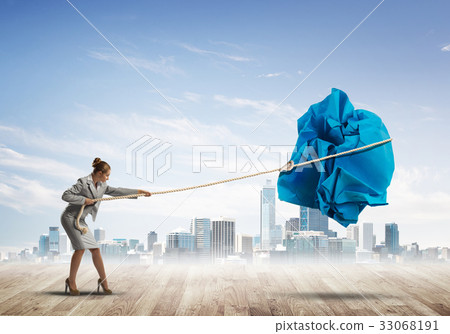 Woman pulling with effort big crumpled ball of paper as creativity sign Woman pulling with effort big crumpled ball of paper as creativity sign 33068191
