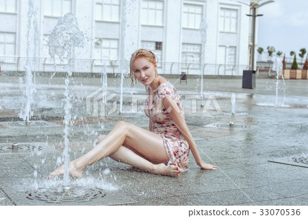 Woman is sitting in a fountain. Woman is sitting in a fountain. 33070536