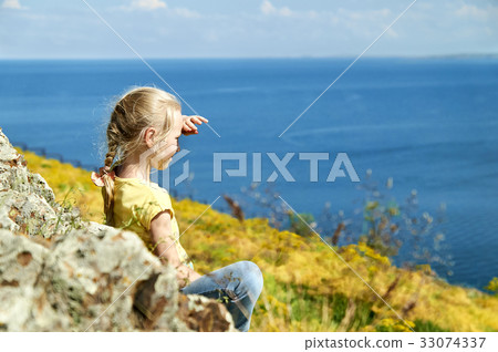 Nice blonde girl sitting on the shore of a lake 33074337