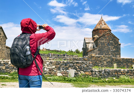 Hiker woman taking photo of ancient monastery 33074374