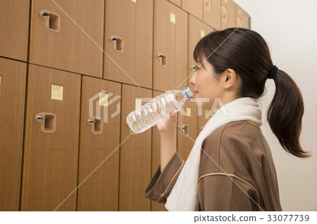 Woman hydrating in locker room of spa facility 33077739