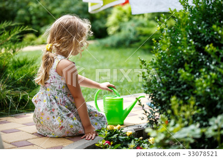 Cute little girl watering plants in the garden. 33078521