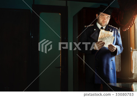 Man in retro uniform stands at the window. 33080783
