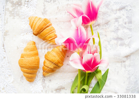 Three croissants and bright pink tulips on lace 33081338
