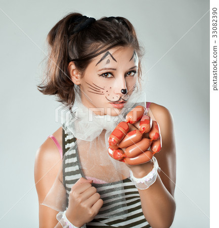 Girl with cat muzzle in his hand holding sausages. Girl with cat muzzle in his hand holding sausages. 33082390