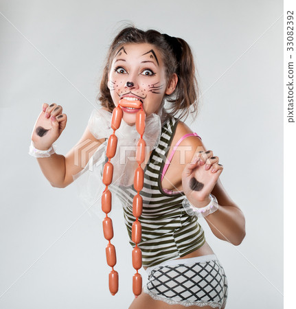 Girl is painted like a cat. Her mouth sausages. Girl is painted like a cat. Her mouth sausages. 33082392