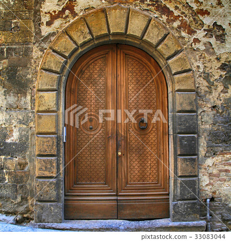 Old brown wooden door in ancient house, Tuscany 33083044