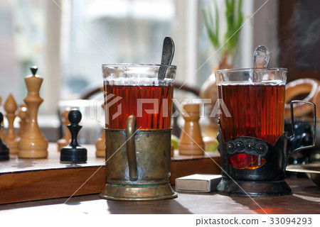 Two glasses of tea in old cupholders on a wooden Two glasses of tea in old cupholders on a wooden 33094293