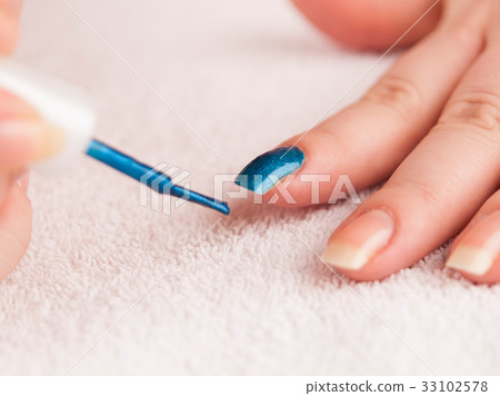 Apply dark blue nail polish on forefinger 33102578
