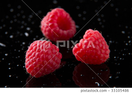 Three raspberry berries on a black background Three raspberry berries on a black background 33105486