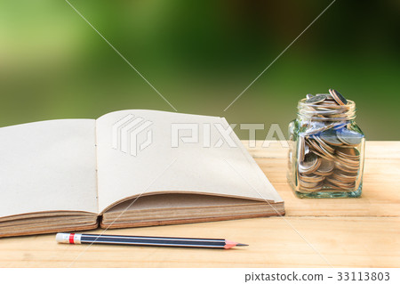 Book and Coin in glass jar on wooden table Book and Coin in glass jar on wooden table 33113803