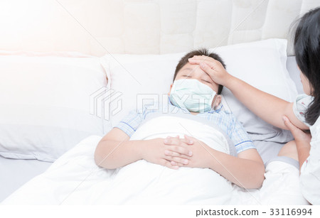 Sick boy with hygienic mask laying on bed 33116994