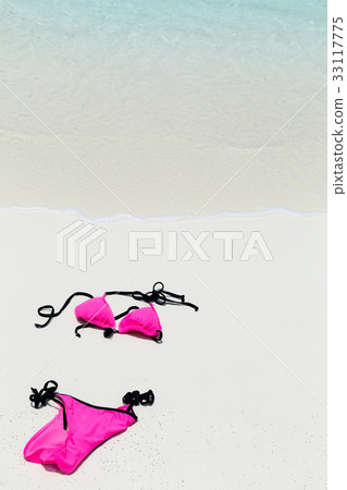 Swimsuit lying on white sand close to sea Swimsuit lying on white sand close to sea 33117775