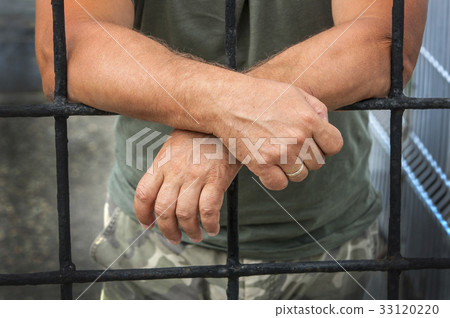 hands of a man behind bars prisons 33120220