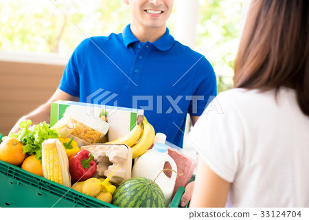 Delivery man delivering food to a woman at home Delivery man delivering food to a woman at home 33124704