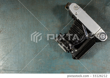 Old vintage camera on a blue scratched background. Old vintage camera on a blue scratched background. 33126212