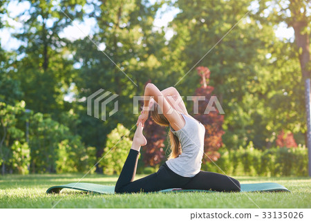 Young woman practicing yoga outdoors at the park 33135026