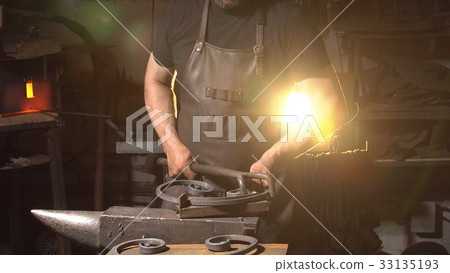 Man works with molten metal in the forge. 33135193