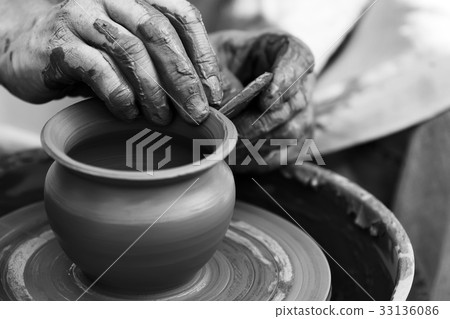 Potter making ceramic pot on the pottery wheel 33136086