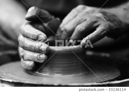 Potter making ceramic pot on the pottery wheel 33136114