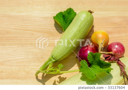 Onion, green courgettes with leaves on a wooden Onion, green courgettes with leaves on a wooden 33137604