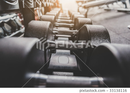 Iron dumbbells locating in row on shelves 33138116