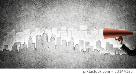 Hand of businesswoman holding red paper trumpet against cityscape background 33144183