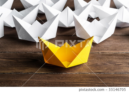 Business leadership concept with white and color paper boats on wooden table Business leadership concept with white and color paper boats on wooden table 33146705