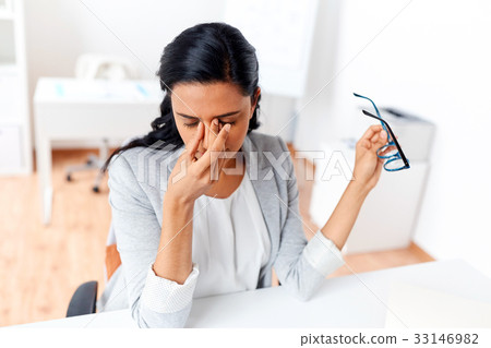 businesswoman rubbing tired eyes at office 33146982
