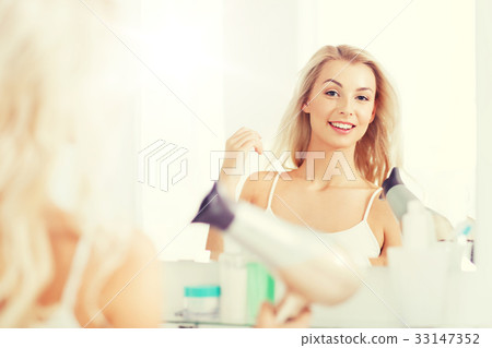 happy young woman with fan drying hair at bathroom 33147352
