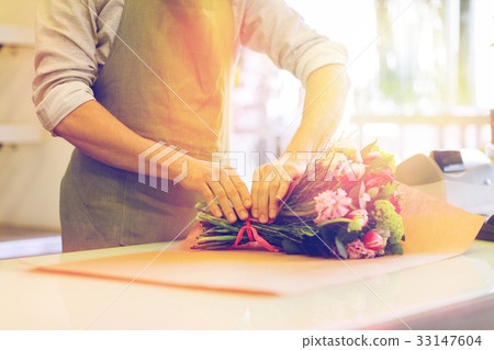 florist wrapping flowers in paper at flower shop 33147604