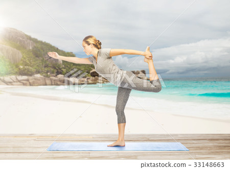 woman in yoga lord of the dance pose on beach 33148663