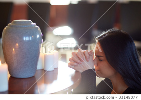 sad woman with funerary urn praying at church sad woman with funerary urn praying at church 33149077
