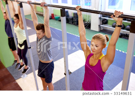 group of people hanging at horizontal bar in gym 33149631