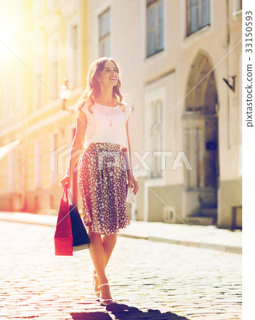 happy woman with shopping bags walking in city 33150593