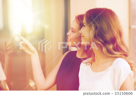 happy young women pointing finger to shop window 33150606