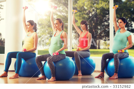 happy pregnant women exercising on fitball in gym 33152982