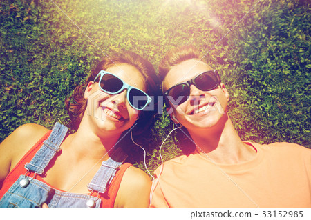 happy teenage couple with earphones lying on grass 33152985