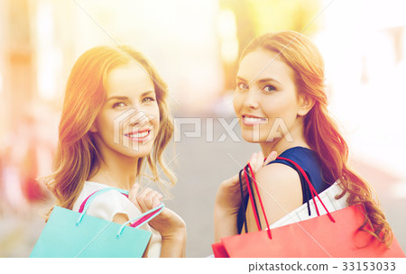 happy women with shopping bags walking in city 33153033