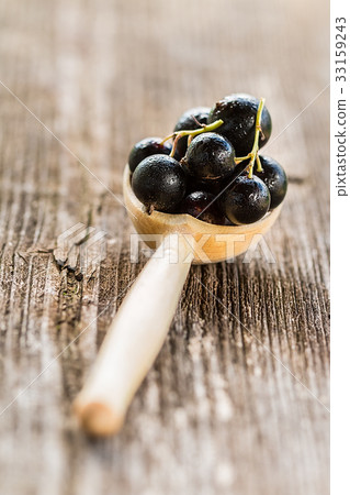 black currant in wooden spoons on rustic  table 33159243