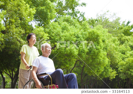 senior man sitting on a wheelchair with his wife 33164513