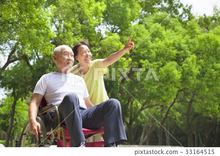 senior man sitting on a wheelchair with his wife senior man sitting on a wheelchair with his wife 33164515