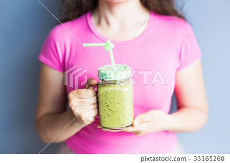 Healthy green smoothie in woman's hand. Vegan, raw Healthy green smoothie in woman's hand. Vegan, raw 33165260